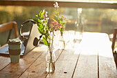 Wildflower arrangement in glass bottle on rustic cafe table
