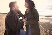 Boyfriend proposing to girlfriend on winter beach
