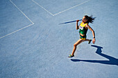 Female athlete throwing javelin on sunny blue track