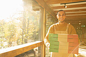 Proud pizzeria owner with pizza boxes at sunny window