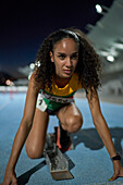 Determined athlete at starting block on track