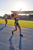 Female athlete celebrating after race on sunny track
