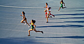 Female athletes running in competition on blue track