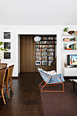 Open-plan interior with dark floor and floor-to-ceiling bookshelves in the background