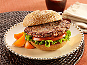 A ground Turkey Burger with tomato and lettuce on a sesame seed bun garnished with orange slices