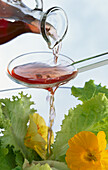 Red wine vinegar flows over a salad spoon onto mixed salad