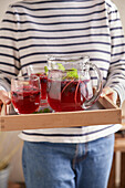 Woman serving Swedish blueberry lemonade on tray