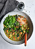 Vegan vegetable stew with carrots, coriander, green peas, spinach, lentils, cauliflower, black sesam seeds and sauerkraut