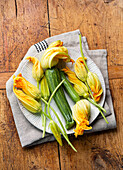 Fresh raw zucchini flowers on dark blue linen tablecloth