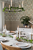 Festively set dining table below candle chandelier
