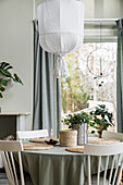 Round table with tablecloth and wooden chairs in front of window