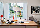 Tablett und Buch auf Küchentheke, im Hintergrund ovaler Essztisch mit Kerzen vor Fenster