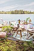 Barbecue and various chairs around festively set table by the lake