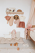Crawling blanket, above it wardrobe with girls' clothes in the children's room in nude shades