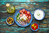 Greek mediterranean salad with tomatoes, feta cheese and cucumber on plate and assorted traditional appetizers
