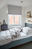 Bett vorm Fenster mit Rollo im Kinderzimmer in Grau und Weiß