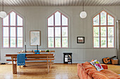 Cosy sofa and dining area with wooden benches in converted chapel