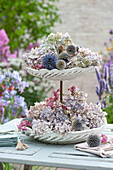 Etagere with hydrangea blossoms, globe thistles and mini roses as table decoration