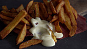 Hand tunkt Pommes in die Mayonnaise