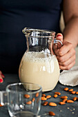 Pouring homemade almond milk into a jug