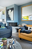 Blau-weiß bezogenes Sofa und hellbrauner Ledersessel im Wohnzimmer