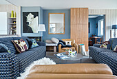 Offener Wohnraum mit blau-weiß bezogenen Sofas und hellbraunen Ledersesseln