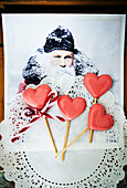 Heart-shaped lollipops on lace paper in front of Father Christmas illustration