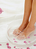 Feet in a bowl of water and rose petals