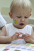 Baby girl playing with sticker book