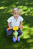 Boy on play vehicle in garden