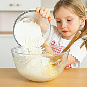 Girl tipping flour from one bowl into another