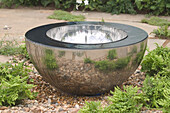 Metal bowl fountain surrounded by ferns