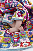 Baby wrapped in colourful baby granny blanket