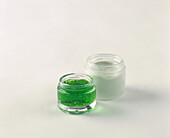 Jar of green gel and a jar of white cream