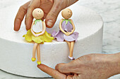 Placing figures of fairies on edge of cake