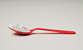 Plastic red teaspoon with white powder