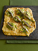 Grilled pizza topped with anchovies and sauteed leeks