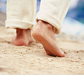 Pair of bare male feet walking on sand