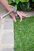Nailing a sheet of artificial turf in place in one corner