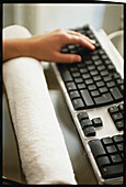 Typing on computer keyboard with wrist resting on towel