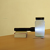 Torch shining through jar containing water and milk