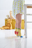 Girl tiptoeing wearing frock and colourful knitted socks