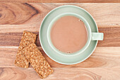Cup of milky tea on saucer with two oat biscuits