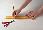Hands drawing line holding yellow ruler and pencil
