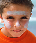 Boy with sun protection lotion smeared on his face