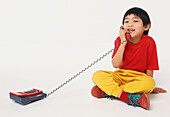 Boy sitting cross-legged using telephone