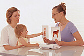 Child pointing to cat card over a dog card held by a woman