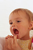 Hand pulling down bottom lip of toddler and checking teeth