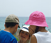 Children whispering to each other on a beach