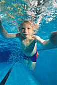 Boy swimming underwater with his eyes open, facing forward